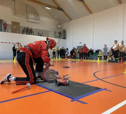 strażacy zwijają węża na hali sportowej